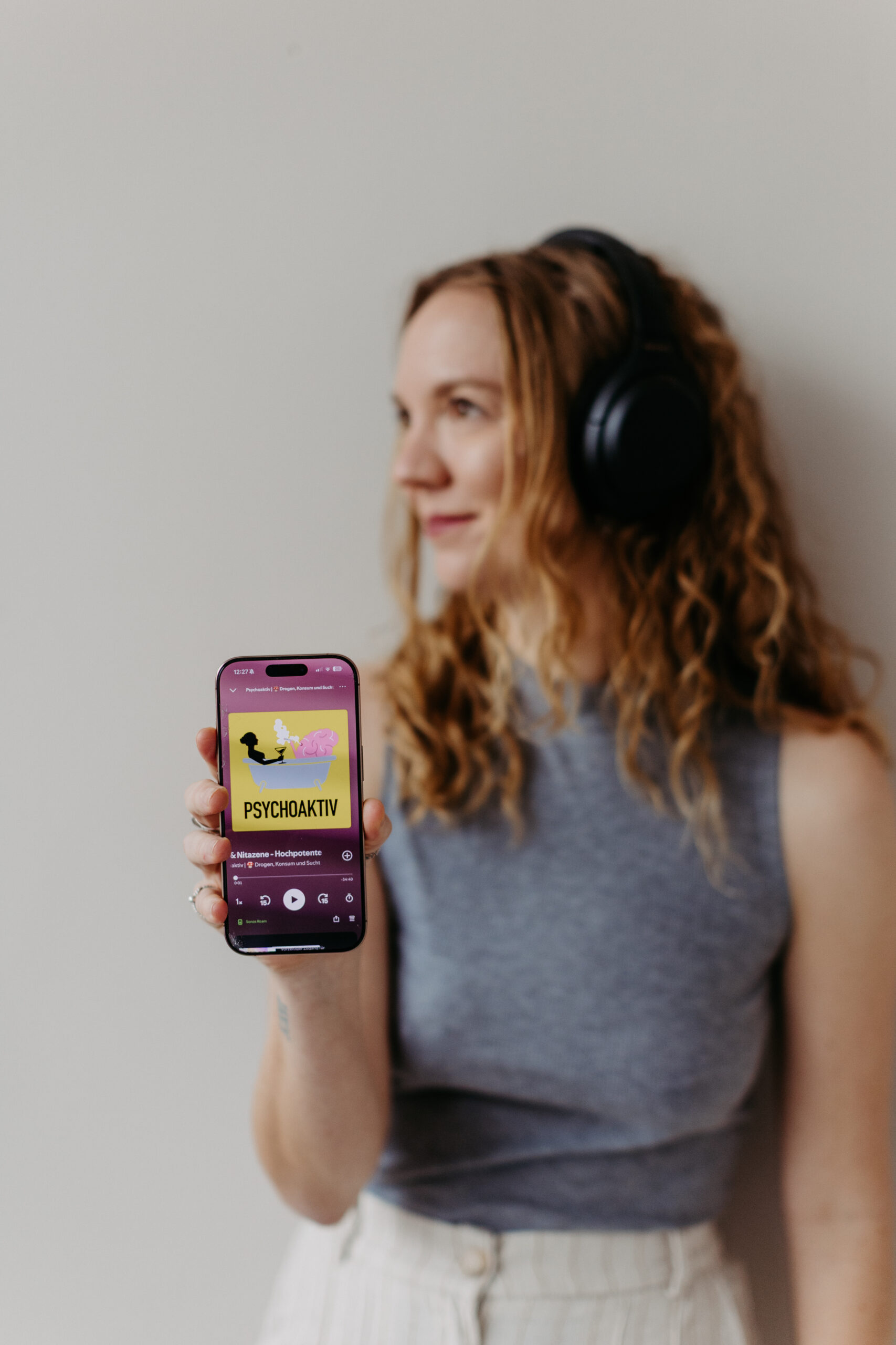 Portrait von Stefanie Bötsch mit Handy das den Psychoaktiv Podcast zeigt, Suchttherapeutin und Gründerin von Psychoaktiv.
